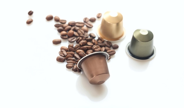 Cápsulas de café espresso y granos de café sobre fondo blanco Vista de primer plano con detalles