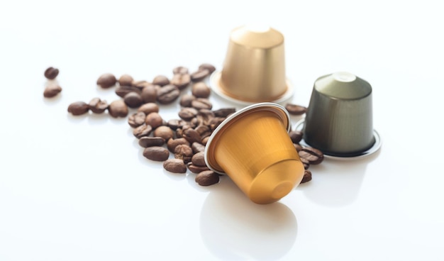 Cápsulas de café espresso y granos de café sobre fondo blanco Vista de primer plano con detalles