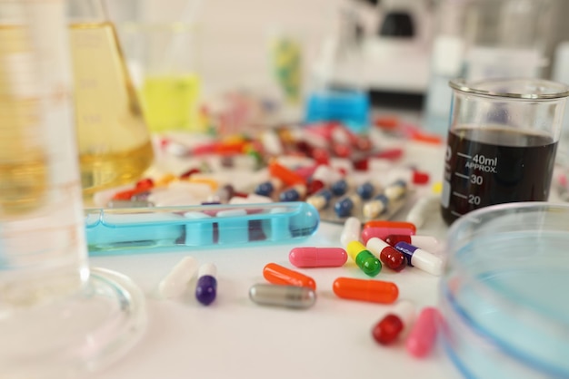 Cápsulas coloridas e amostras em um tubo de ensaio sobre a mesa no laboratório médico fechado