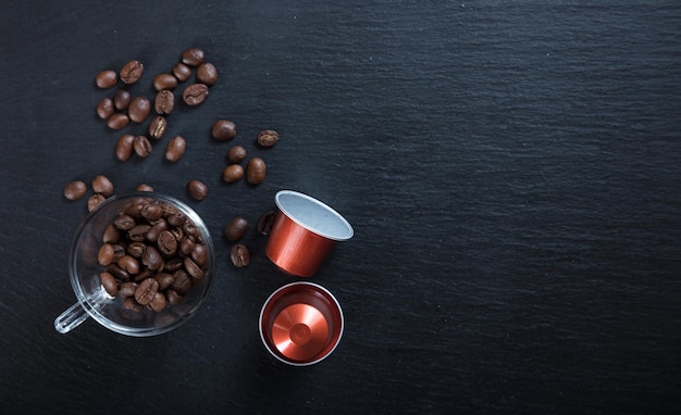 Cápsulas de café expresso e grãos em fundo preto Vista superior com espaço para cópia