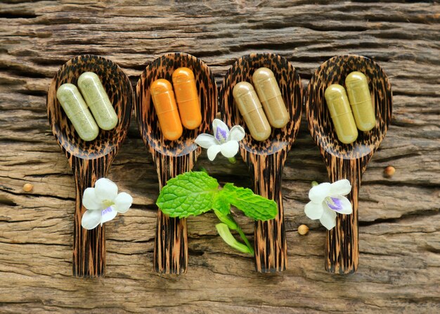 Foto cápsulas de ervas medicinais na mesa de madeira