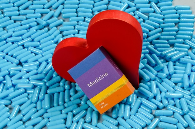 Cápsulas con forma de corazón y medicamentos que representan problemas cardíacos y tratamiento