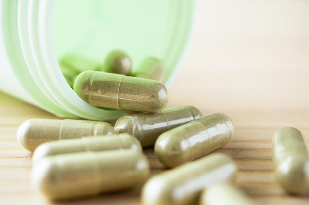 Foto cápsulas de hierbas medicinales con botella sobre mesa de madera