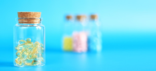 Cápsulas de Omega 3 en un frasco de vidrio sobre un fondo azul Píldoras médicas para el cuidado de la salud