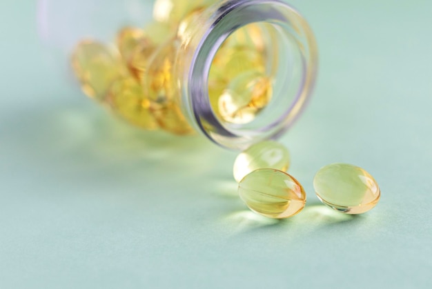 Cápsulas omega3 amarillas de una botella de vidrio sobre un fondo verde Copyspace para texto Cuidado de la salud suplementos naturales naturales Concepto de estilo de vida