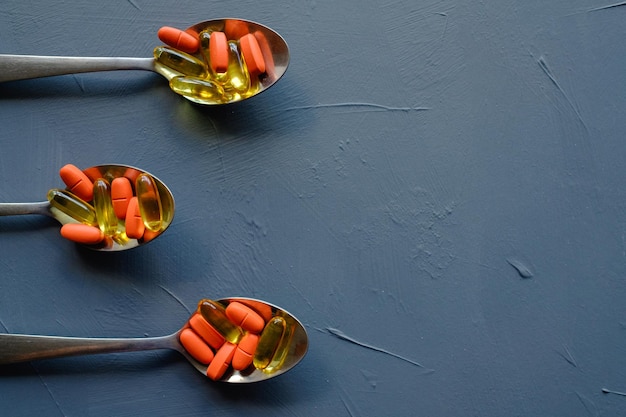 Cápsulas de pastillas en cucharas analgésicos y medicamentos recetados sobre fondo azul.