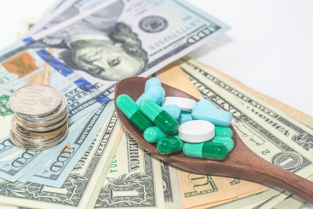 Cápsulas, pastillas y medicamentos se juntan con dólares y monedas.