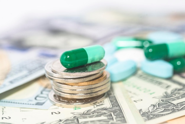 Cápsulas, pastillas y medicamentos se juntan con dólares y monedas.