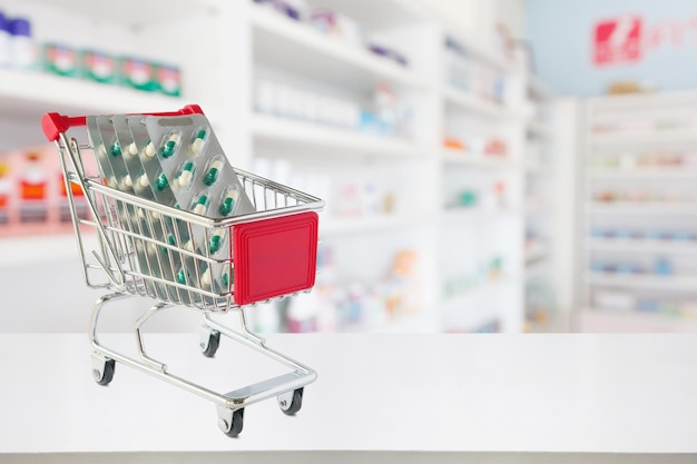 cápsulas de pastillas de medicina en el carrito de compras en el mostrador de la farmacia con estantes borrosos de la farmacia fondo desenfocado
