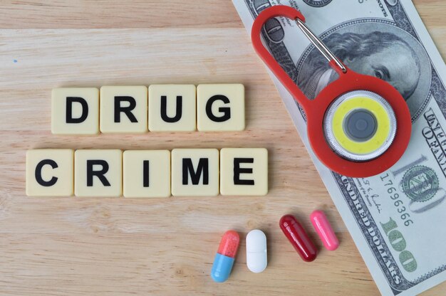 Foto cápsulas de píldoras de candado de juguete, billetes de dinero y letras cuadradas con texto delito de drogas