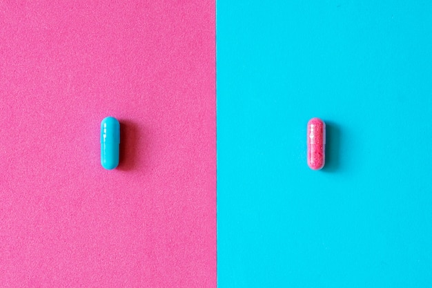 Cápsulas rosadas y azules, píldoras aisladas en fondo rosado y azul