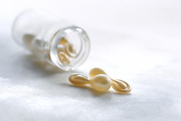 Cápsulas de suero para una piel sana Primer plano en botella transparente con cápsulas doradas metálicas