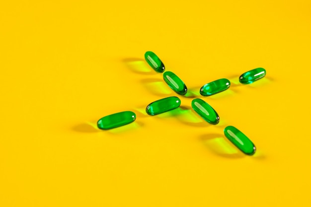 Cápsulas transparentes verdes dobradas sob a forma de uma cruz. o conceito de farmacologia.