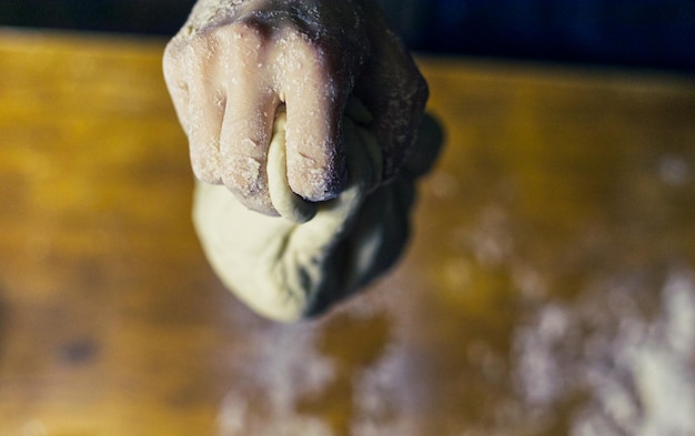 Captura aproximada das mãos do padeiro fazendo massa para pão em uma mesa de madeira