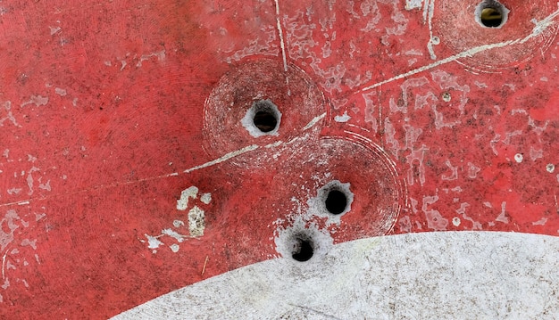 Foto captura aproximada de buracos de bala em uma velha placa de rua enferrujada