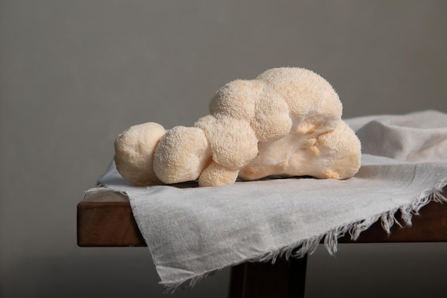 Captura aproximada de cogumelos juba de leão branco sobre um pano branco colocado sobre uma mesa de madeira