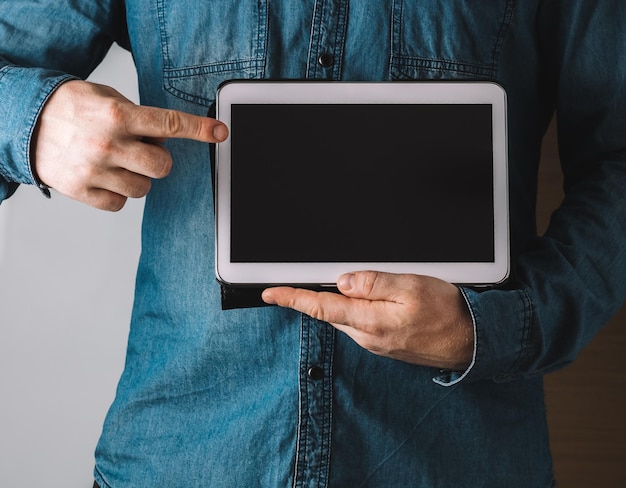 Captura aproximada de um homem segurando e apontando para um tablet com uma tela em branco