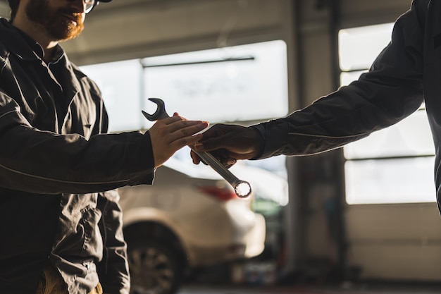 Captura aproximada de um mecânico dando uma chave para seu colega em uma oficina mecânica