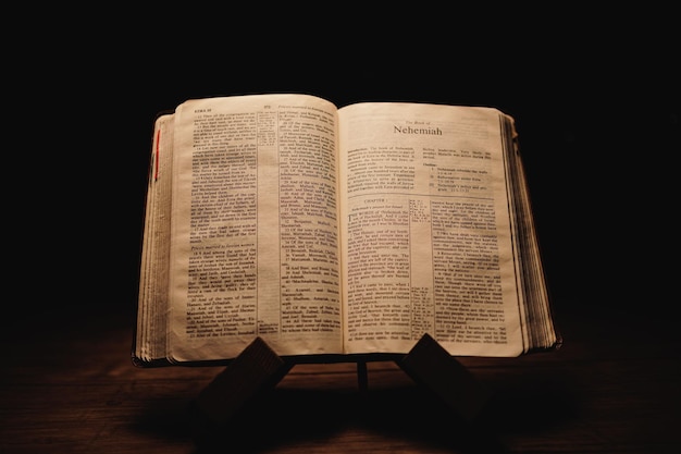 Captura aproximada de uma Bíblia antiga histórica aberta nas páginas de Neemias em exposição num quarto escuro