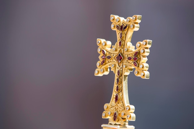 Foto captura aproximada de uma cruz armênia de ouro sobre um fundo cinza