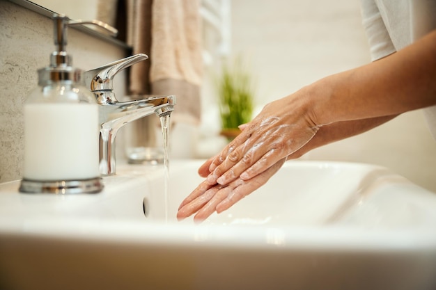 Captura aproximada de uma mulher irreconhecível lavando as mãos com sabão para prevenir o Coronavírus.