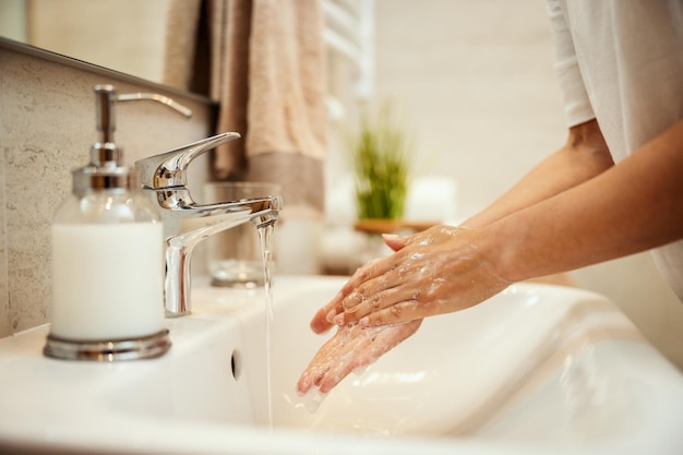 Captura aproximada de uma mulher irreconhecível lavando as mãos com sabão para prevenir o Coronavírus.