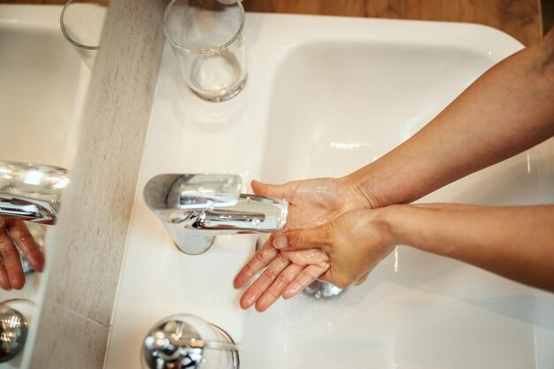 Captura aproximada de uma mulher irreconhecível lavando as mãos com sabão para prevenir o Coronavírus.