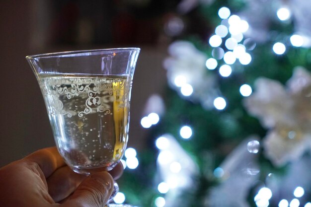 Foto captura aproximada de uma taça de champanhe no fundo das luzes de natal
