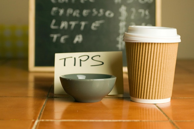 Captura aproximada de xícara de café de plástico e tigela para dicas com fundo de lista de preços