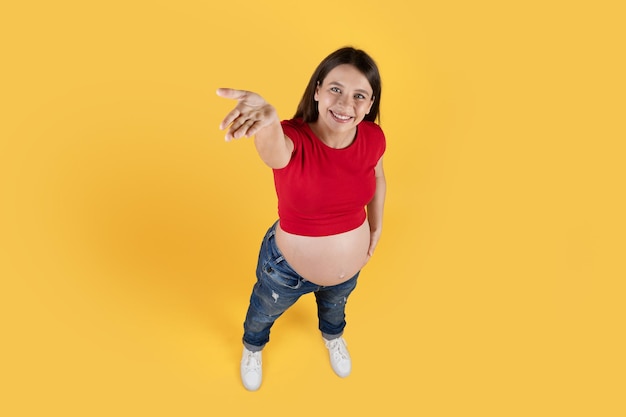 Captura de arriba de una joven embarazada positiva demostrando algo en la palma vacía