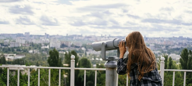 Captura de faixa de uma mulher loira olhando para a cidade através de alguns grandes binóculos
