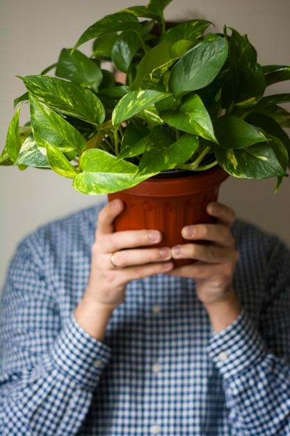 Captura de um homem segurando um pote de scindapsus com uma planta perto de sua cabeça de publicidade mocap