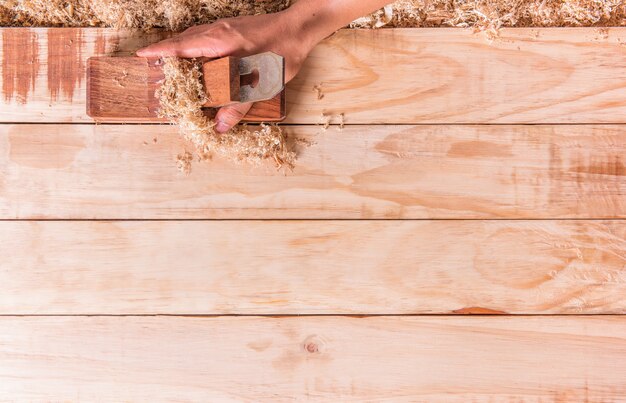 La captura de la mano es un avión Carpenter en una tabla de madera con suavizado