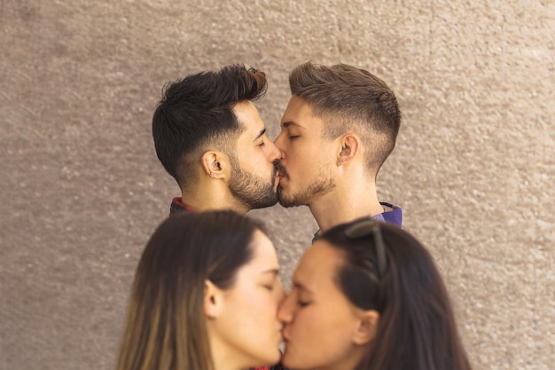 Captura média de um casal gay se beijando nos lábios na frente de um casal de lésbicas turva