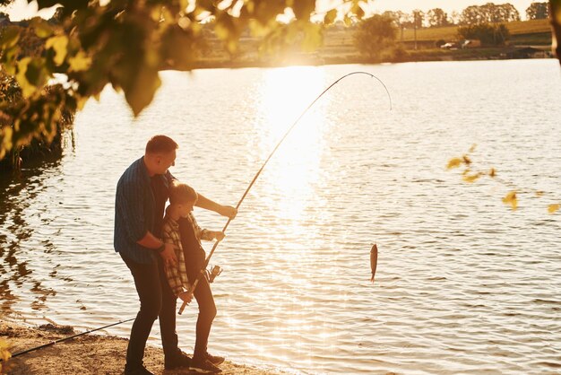 Con captura Padre e hijo pescando juntos al aire libre en verano