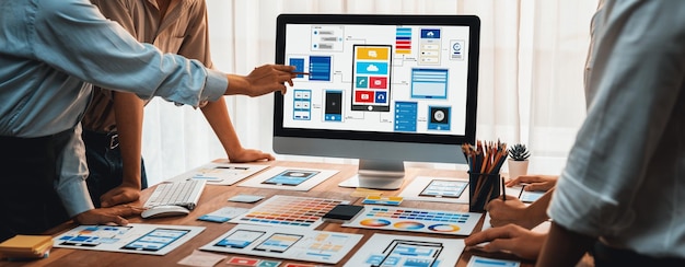 Captura panorámica del equipo de desarrolladores de interfaz de usuario haciendo una lluvia de ideas sobre diseños de UI y UX para aplicaciones móviles en la pantalla de una computadora portátil Planificación del equipo de desarrollo de interfaz de usuario para un diseño de UI fácil de usar Examinar