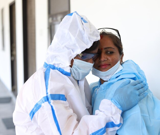 Captura de pantalla de dos médicos indios con uniforme médico consolándose unos a otros sobre un fondo blanco