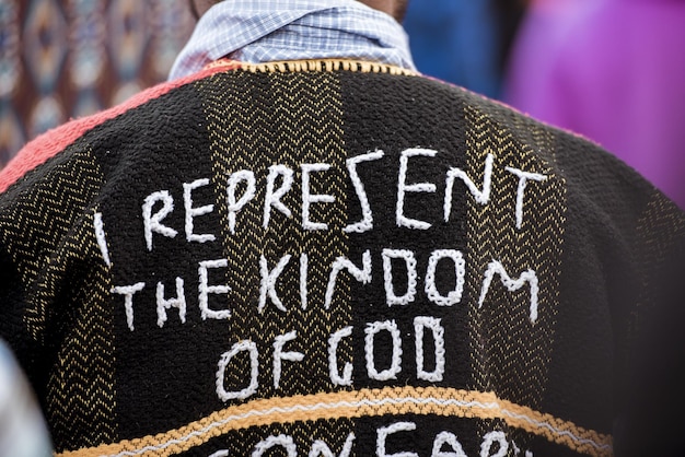 Captura de pantalla de la espalda de una persona con un abrigo que dice "Represento el reino de Dios" cosido en él