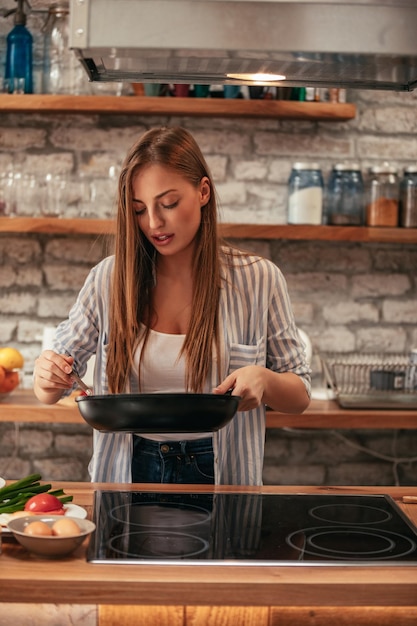 Captura recortada de una atractiva joven rubia en la cocina