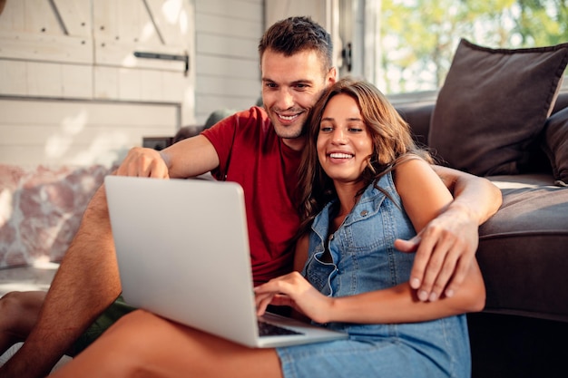 Captura recortada de una atractiva pareja joven usando una computadora portátil en casa