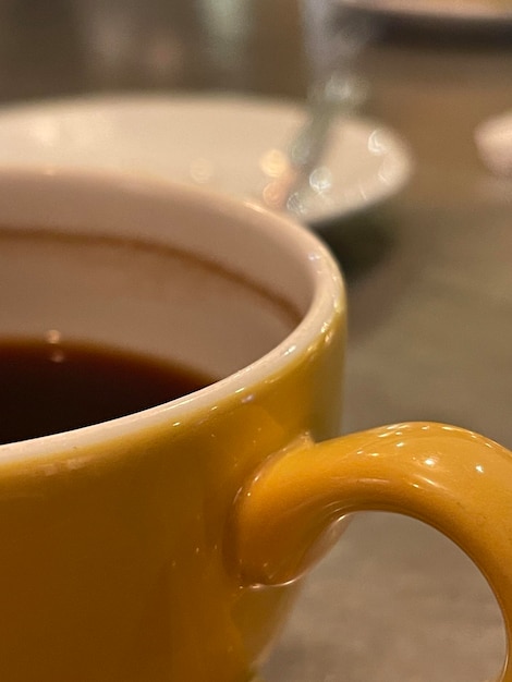 Captura recortada de café negro servido en una taza amarilla