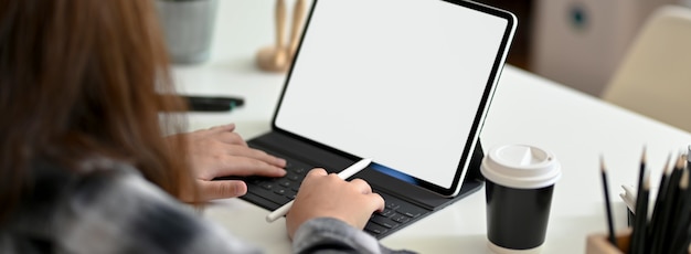Captura recortada de diseñador gráfico femenino escribiendo en la tableta de la pantalla en blanco en la mesa de trabajo