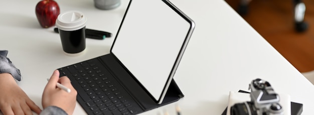 Captura recortada de diseñador gráfico femenino trabajando en tableta de pantalla en blanco en la mesa de trabajo