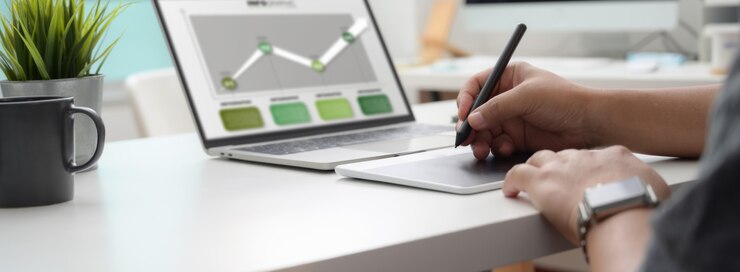 Foto captura recortada del diseñador gráfico que trabaja en un proyecto de infografía con tableta de dibujo y computadora portátil
