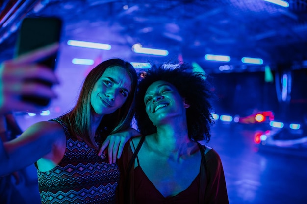 Captura recortada de dos mujeres jóvenes posando para un selfie en el parque de diversiones Tonos azules