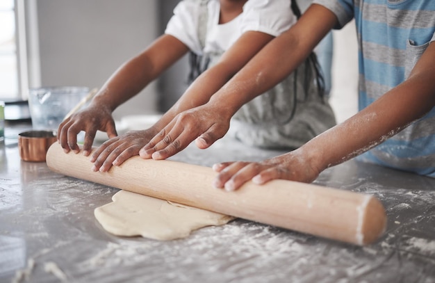 Captura recortada de dos niños irreconocibles divirtiéndose mientras hornean en la cocina en casa