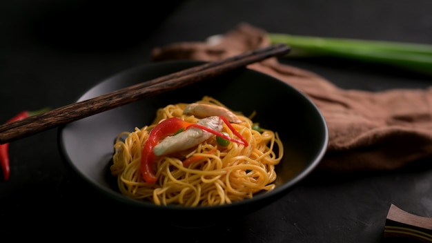 Captura recortada de fideos Schezwan o Chow Mein en un tazón negro con palillos