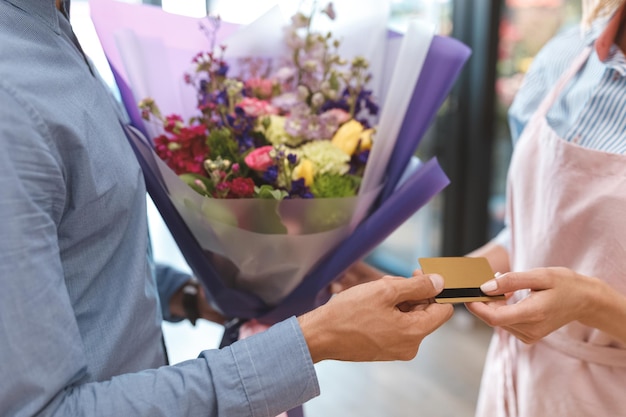 Captura recortada de floristería dando ramo al cliente pagando con tarjeta de crédito