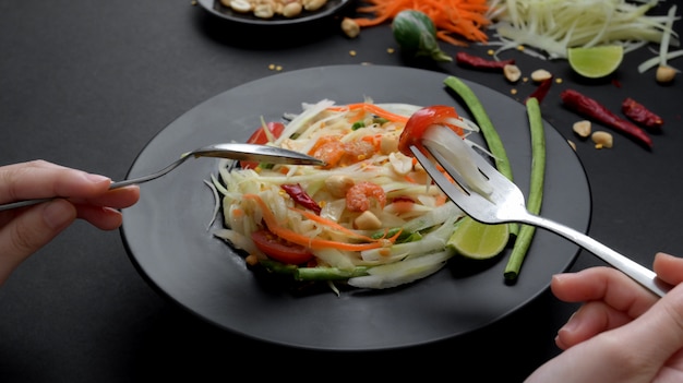 Captura recortada de un hombre comiendo ensalada de papaya en un plato negro