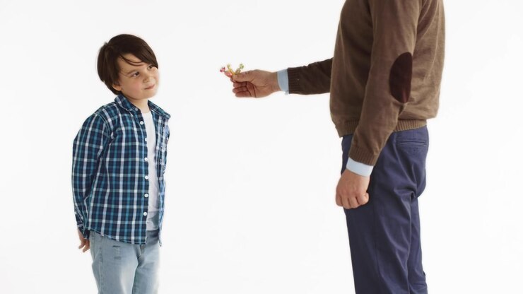 Captura recortada del hombre dando dulces al niño preadolescente aislado sobre fondo blanco.